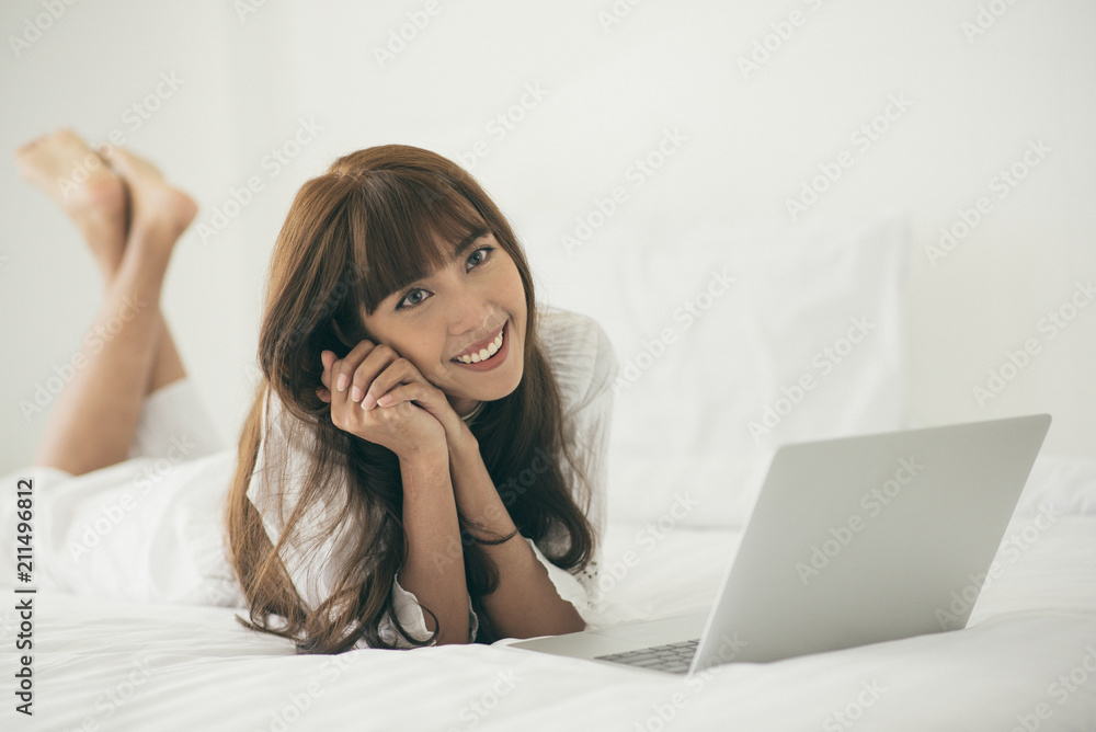 Smiling young woman using laptop working at home with laptop in bed Smiling young woman using laptop working at home with laptop in bed