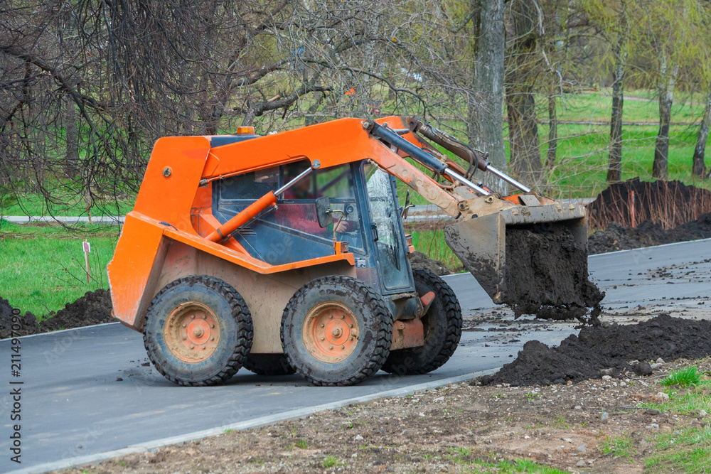 Small bulldozer unloads black soil. Works on the development of the park area. Small bulldozer unloads black soil. Works on the development of the park area.