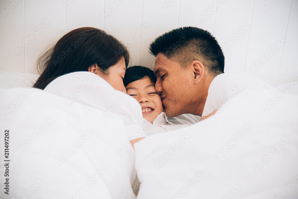 Happy aian family lying in bed and sleeping. Happy aian family lying in bed and sleeping.