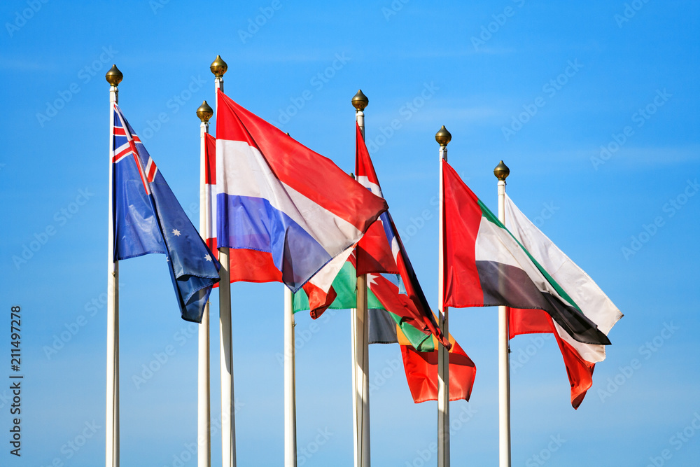 Flags of different countries flutters in the wind a background of blue sky Flags of different countries flutters in the wind a background of blue sky