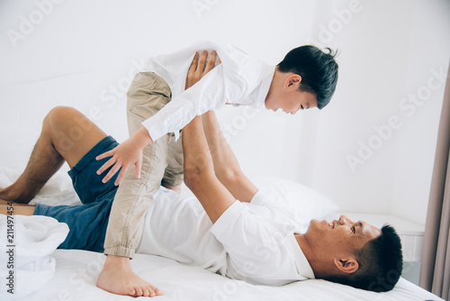 Happy family. Dad and son playing and laughing in bed room.