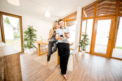 Portrait of a young and happy couple standing together in the cozy interior of the modern wooden house