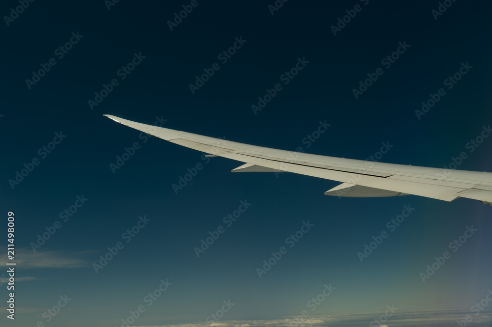Fototapeta premium Wing of airplane flying above the clouds in the sky