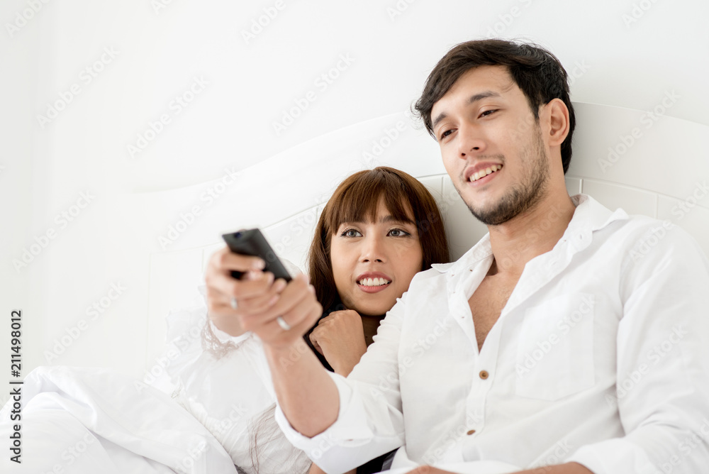 An attractive young couple lying in bed and watching movie. An attractive young couple lying in bed and watching movie.