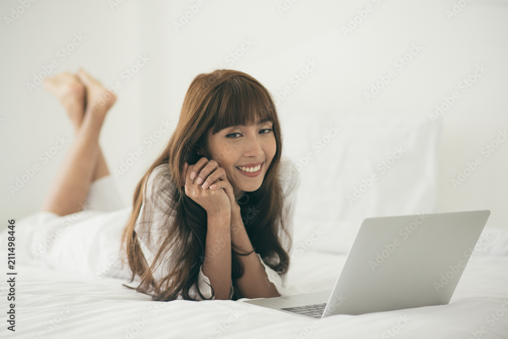 Smiling young woman using laptop working at home with laptop in bed Smiling young woman using laptop working at home with laptop in bed