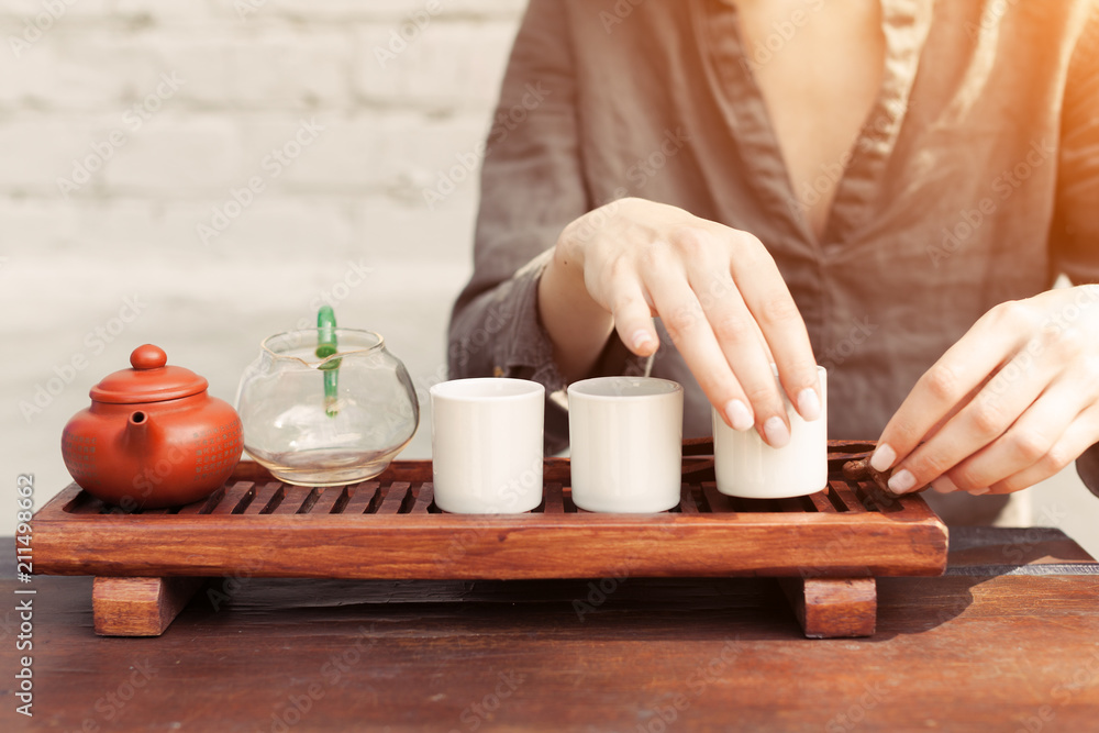 a girl in a gray linen shirt arranges a royal ceremony, classical accessories for a tea ceremony. Concept of healthy food and traditional drinks a girl in a gray linen shirt arranges a royal ceremony, classical accessories for a tea ceremony. Concept of healthy food and traditional drinks