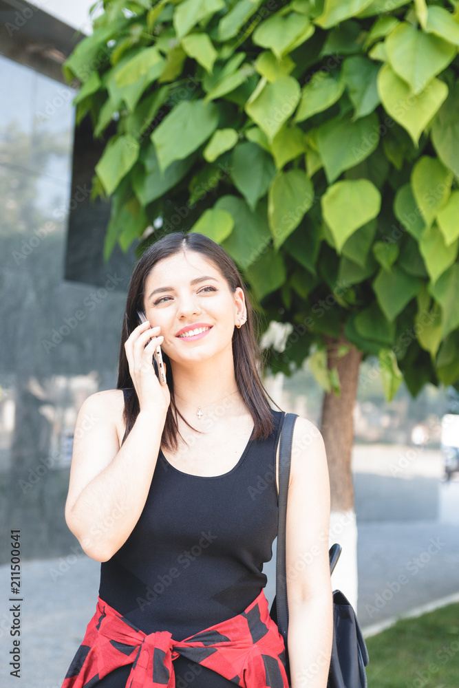 Attractive brunette businesswoman talking on mobile phone with client in the street Attractive brunette businesswoman talking on mobile phone with client in the street