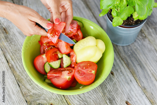 Woman hand slicing tomatoes for a healthy salad 