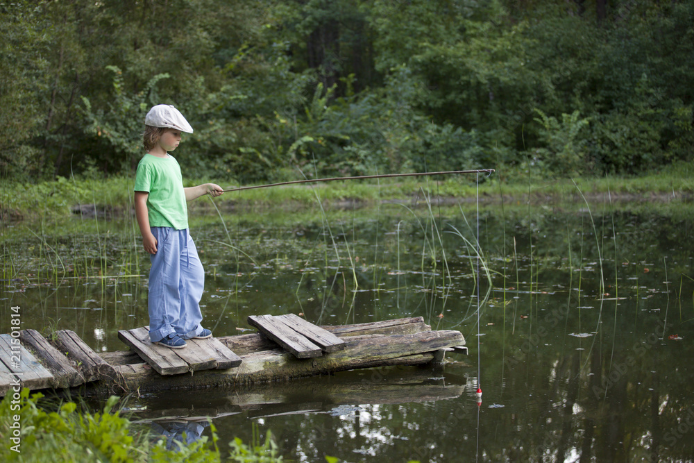 Happy boy go fishing on the river, one children fisherman with a fishing rod on the shore of lake Happy boy go fishing on the river, one children fisherman with a fishing rod on the shore of lake