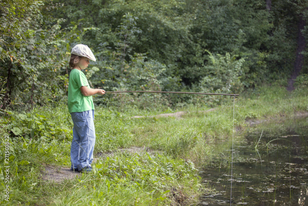 Happy boy go fishing on the river, one children fisherman with a fishing rod on the shore of lake Happy boy go fishing on the river, one children fisherman with a fishing rod on the shore of lake
