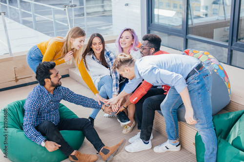 Young jouful group of multiethnic designers male and female giving five after signing contract with partners abroad on the outdoor office terrace. photo