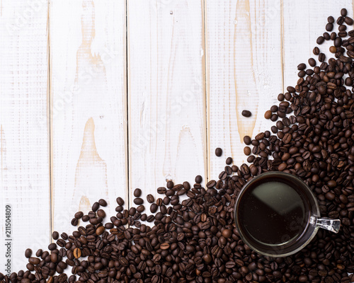 Coffee cup and coffee beans on white wooden table