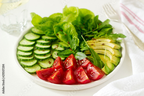Vegetable salad with avocado and flax seeds on a light background, vegan food.