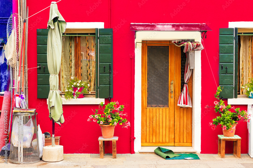 Obraz premium Red house with flowers and plants. Colorful house in Burano island near Venice, Italy