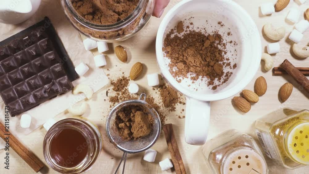 A woman pours cocoa powder into a white mug and pour boiling water A woman pours cocoa powder into a white mug and pour boiling water