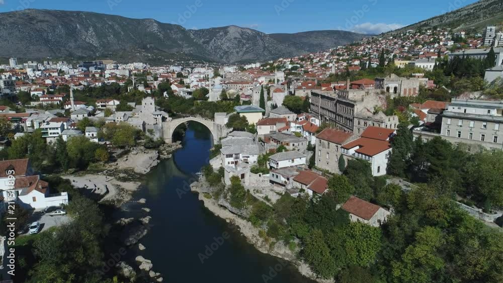 Fast drone shot flying over Neretva river and iconic rebuilt Stari Most stone bridge, reveals Mostar old town, tourism architecture travel Bosnia and Herzegovina