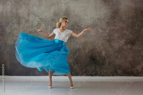 Beautiful young woman in a lush blue skirt, whirling and dancing.
