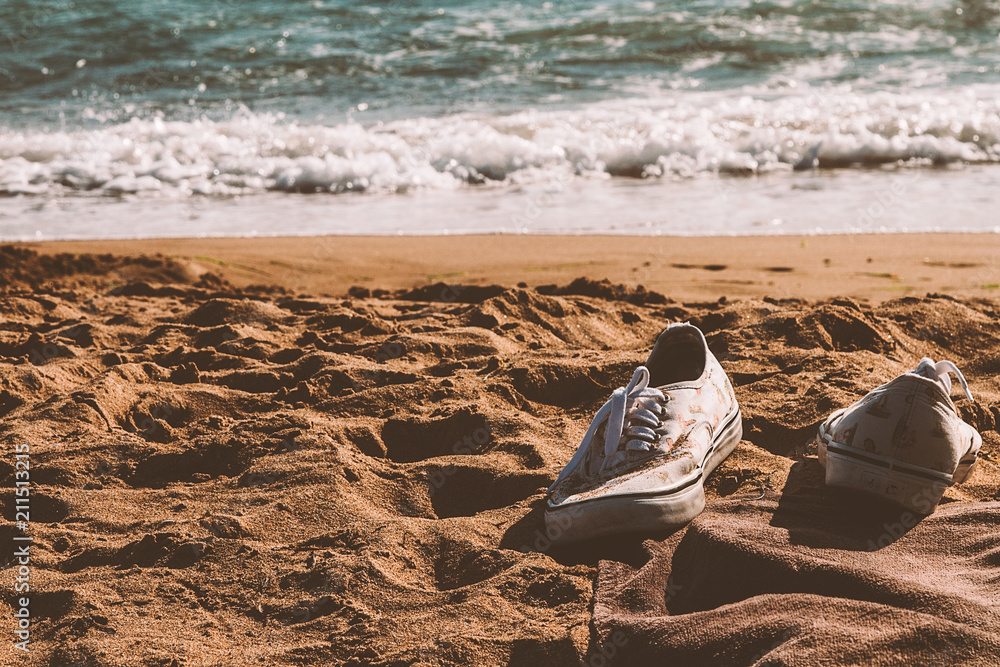 Obraz premium Sneakers left in a sandy beach 