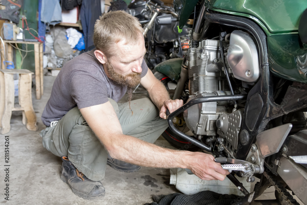 Man repairing the motorcycle in the garage, close-up Man repairing the motorcycle in the garage, close-up