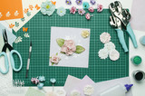 Multi-colored paper crafts on the cutting Mat and scrapbooking tools, top view