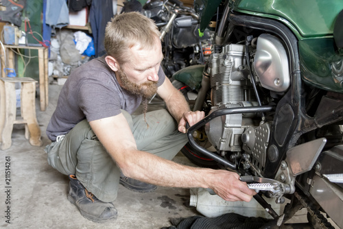 Man repairing the motorcycle in the garage, close-up