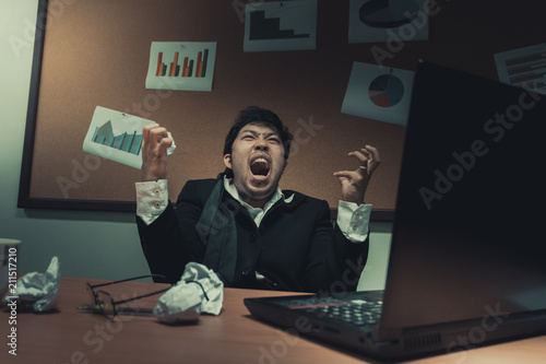 Asian businessman under stress due to excessive work,Feeling exhausted,Young clerk has a problem in a office,sad man from work,Angry messy man concept