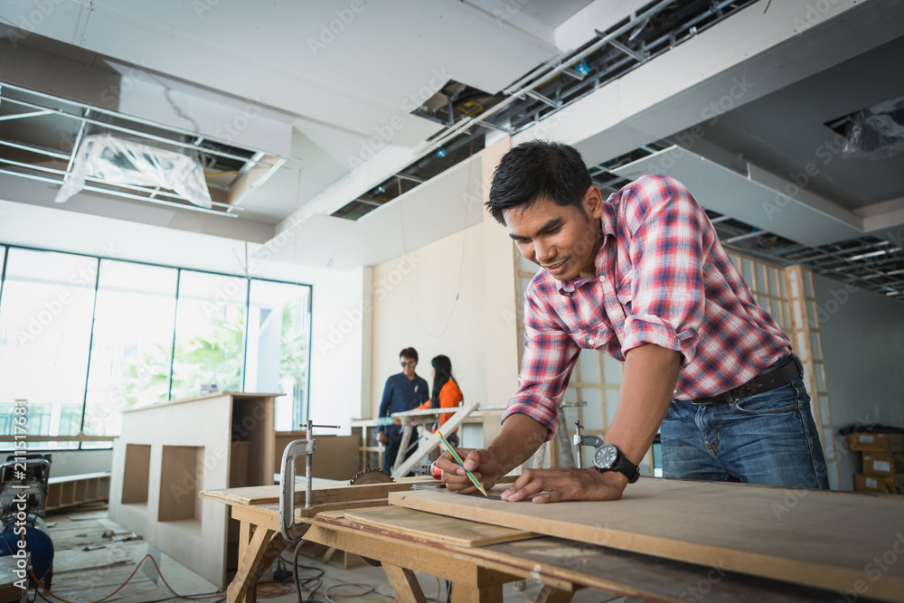 decorator working on design and inspect of plywood at construction site; decorator checking material for interior decorator working on design and inspect of plywood at construction site; decorator checking material for interior