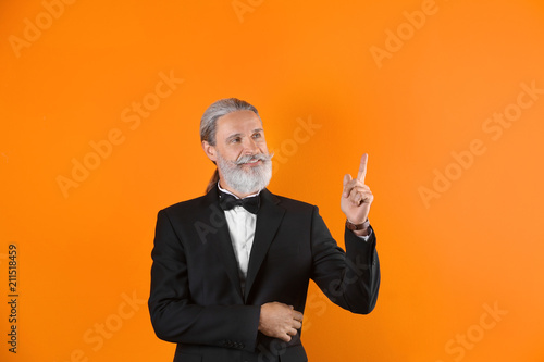 Handsome bearded mature man in suit on color background