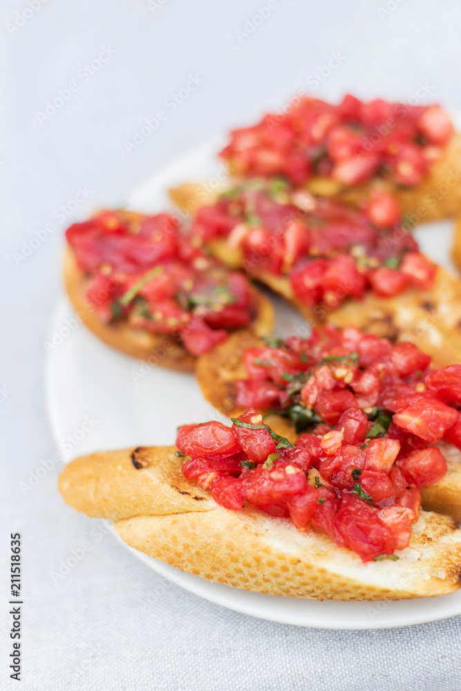 White plate with vegetarian bruschetta with tomatoes and basil White plate with vegetarian bruschetta with tomatoes and basil