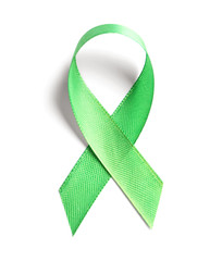 Green ribbon on white background, top view. Cancer awareness