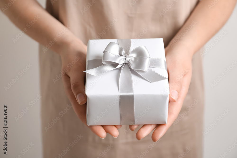 Woman holding gift box on light background Woman holding gift box on light background