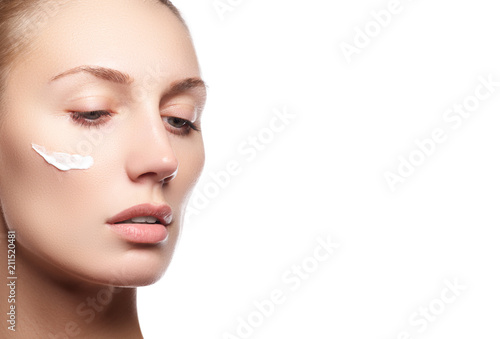 Beauty makeup. Skin care face. Attractive girl on white background. Beautiful face of young woman with cosmetic cream on a cheek. Skin care concept. Skincare products
