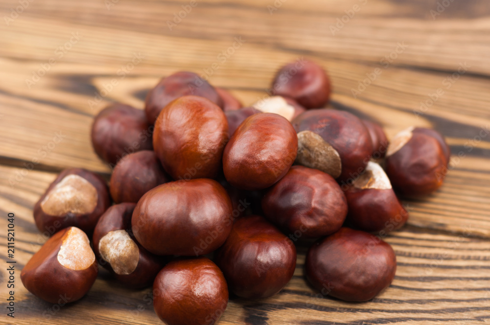 Heap of brown chestnuts on old wooden rustic brown table Heap of brown chestnuts on old wooden rustic brown table