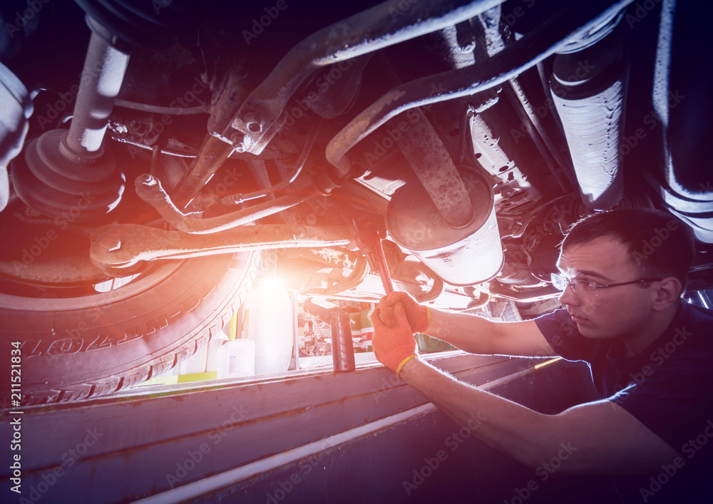 Fototapeta premium Car mechanic repair car suspension of lifted automobile at repair service station