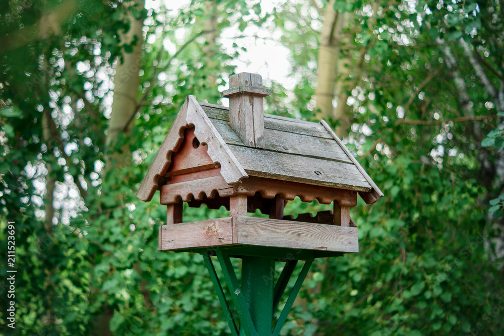Wooden bird feeder in the background of trees in summer Wooden bird feeder in the background of trees in summer