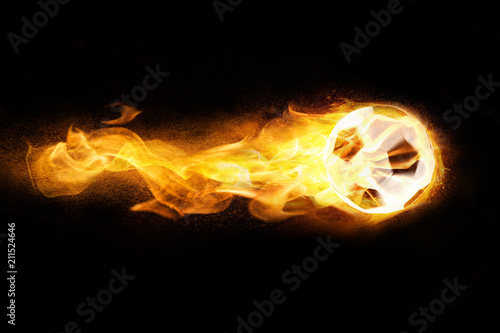 Klassischer Fu  ball aus Leder brennt mit Feuerschweif und Funken auf schwarzem Hintergrund
