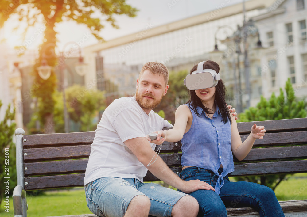 A young couple plays a game using virtual reality glasses on the street.