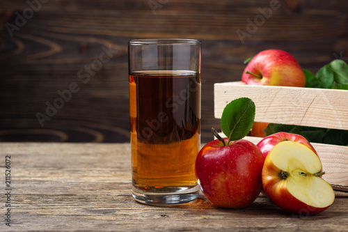 Glass of apple juice with red apples on wooden table