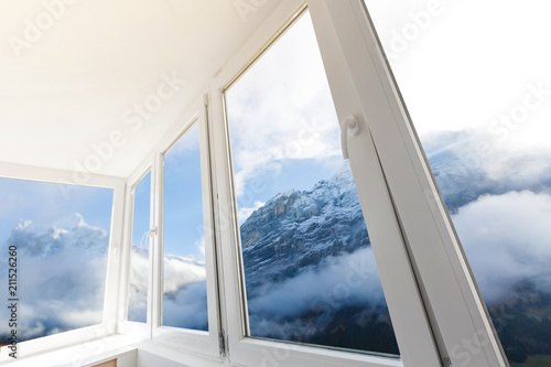 White metal-plastic windows of balcony in modern apartment panoramic view mountains
