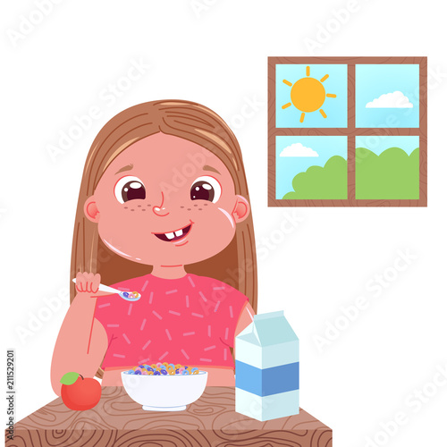 A baby girl eats breakfast in the morning. Sweet dish colourfull corn flakes with milk. Outside the window is a  day and the sun.
