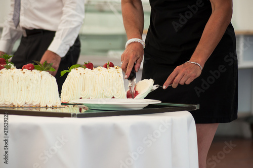 closeup of woman cutting wedding cake in reception room