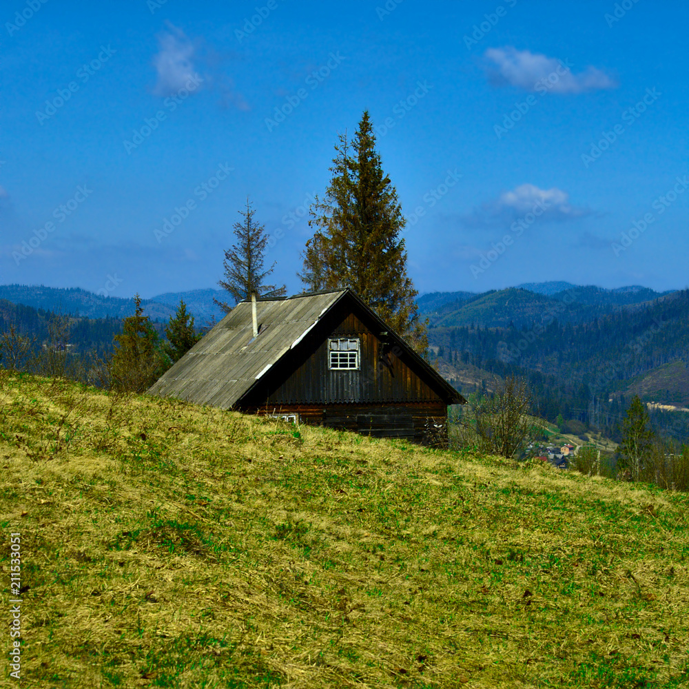 old wooden house in the mountains behind the slope
