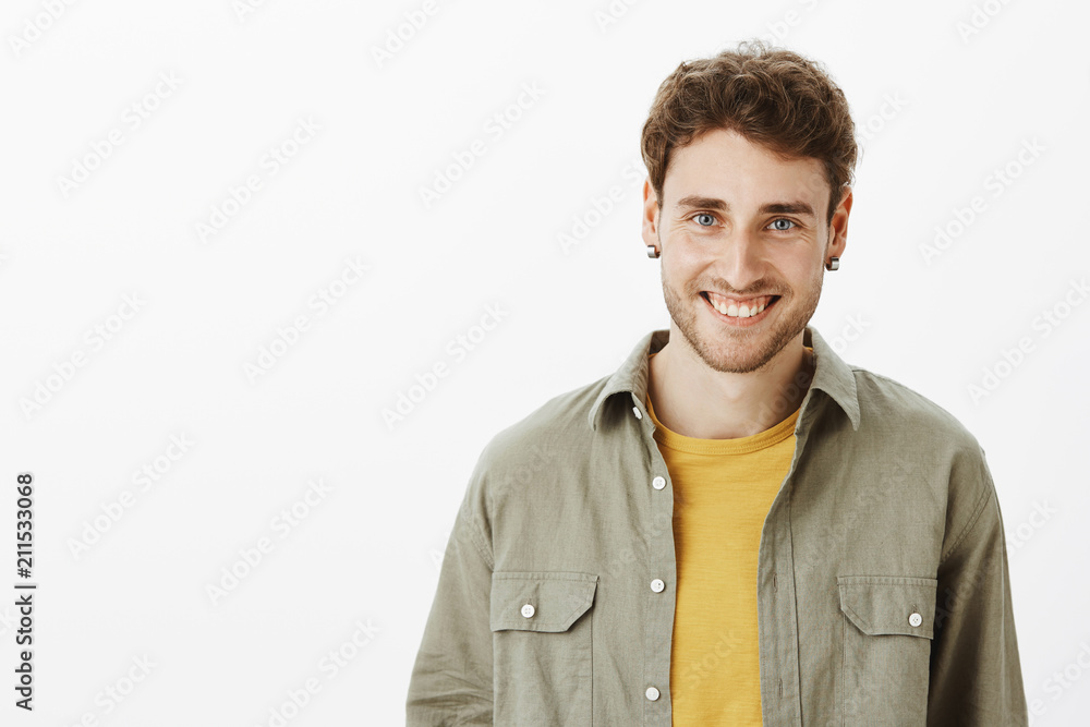 Charming emotive guy with beard and beautiful blue eyes smiling joyfully and smiling broadly at camera from potisive emotions, having fun while hanging out on party, standing over gray background Charming emotive guy with beard and beautiful blue eyes smiling joyfully and smiling broadly at camera from potisive emotions, having fun while hanging out on party, standing over gray background