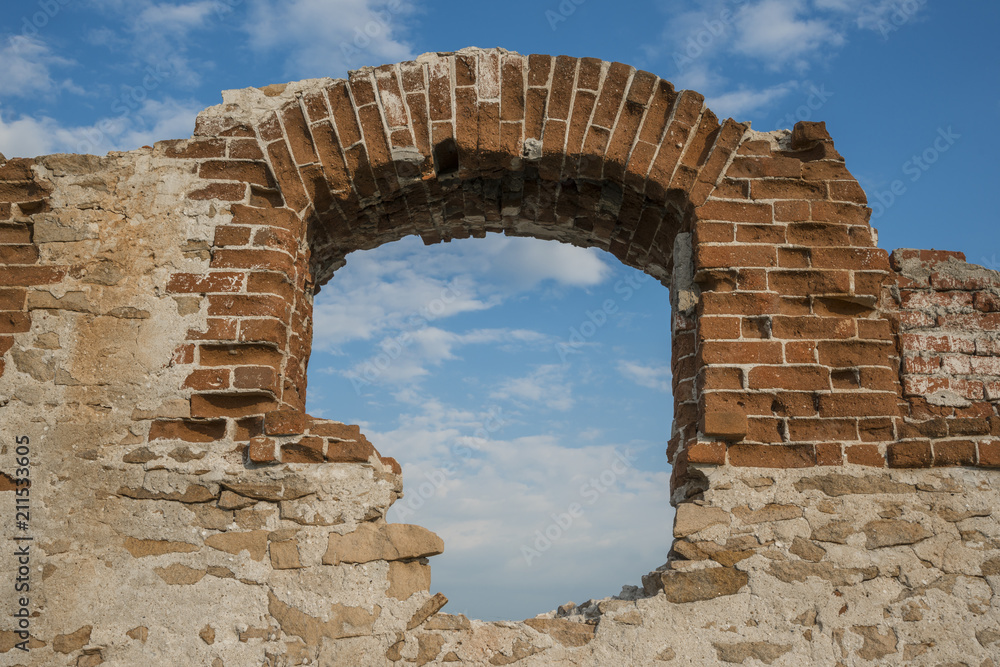 Window arch of an old abandoned building, against a sky with clouds