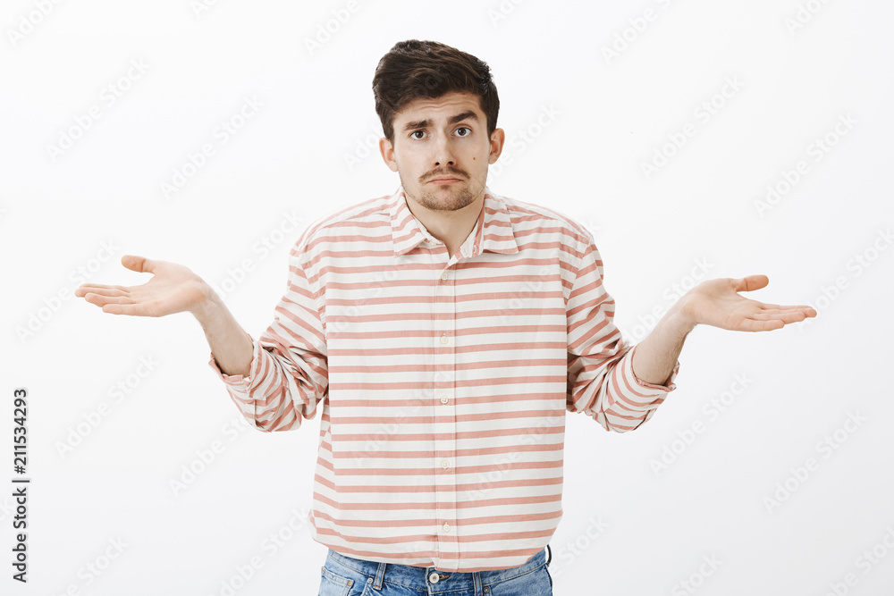 No clue, no guesses. Portrait of gloomy unsure boyfriend with moustache, shrugging with spread palms, being confused and unaware what is happening, standing clueless over gray background No clue, no guesses. Portrait of gloomy unsure boyfriend with moustache, shrugging with spread palms, being confused and unaware what is happening, standing clueless over gray background