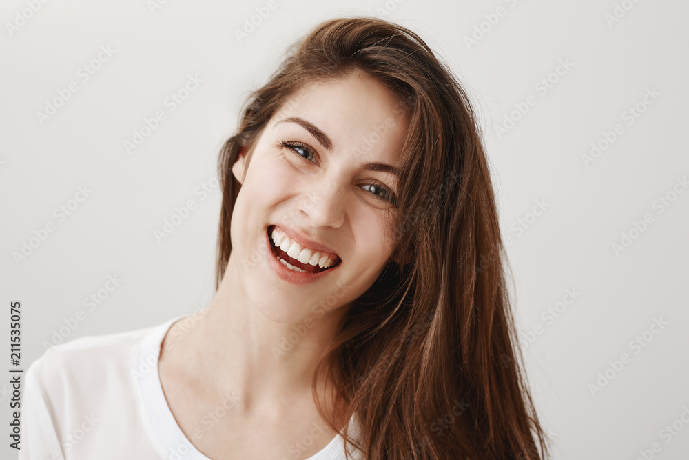 Sincere expression of joy. Portrait of attractive happy caucasian female coworker standing over gray background, tilting head and laughing out loud, being in great positive mood, hearing funny joke Sincere expression of joy. Portrait of attractive happy caucasian female coworker standing over gray background, tilting head and laughing out loud, being in great positive mood, hearing funny joke