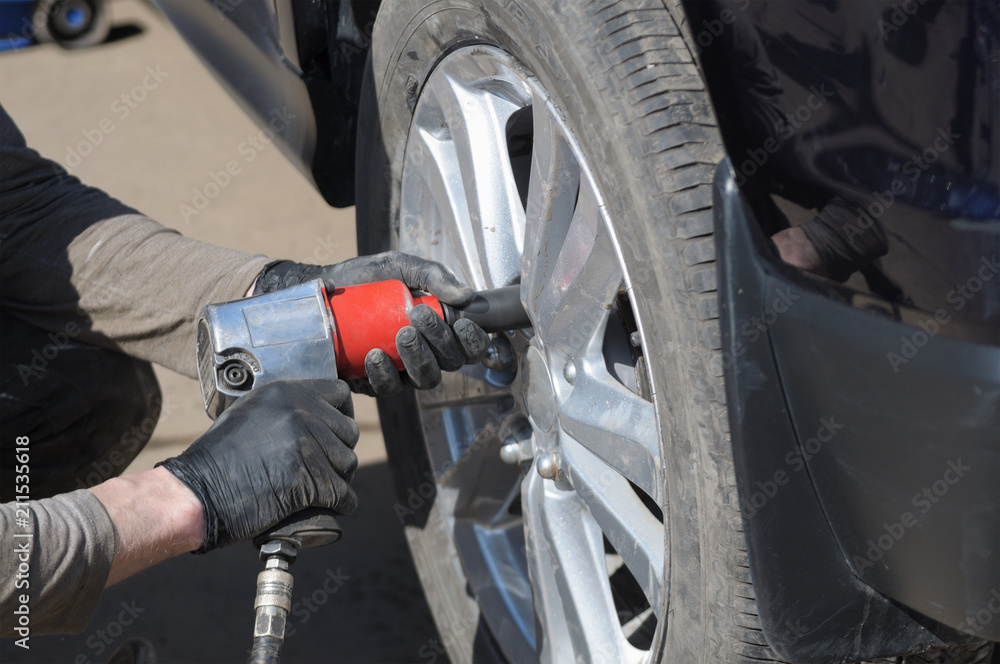 Fototapeta premium mechanic changes the wheel on a modern car