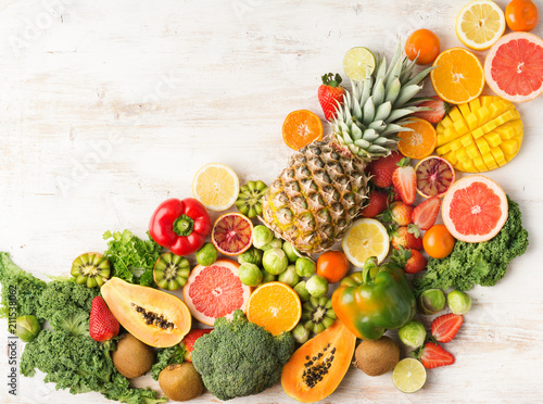 Fruits and vegetables rich in vitamin C arranged diagonally oranges mango grapefruit kiwi kale pepper pineapple lemon sprouts papaya broccoli  on white table  top view  copy space  selective focus