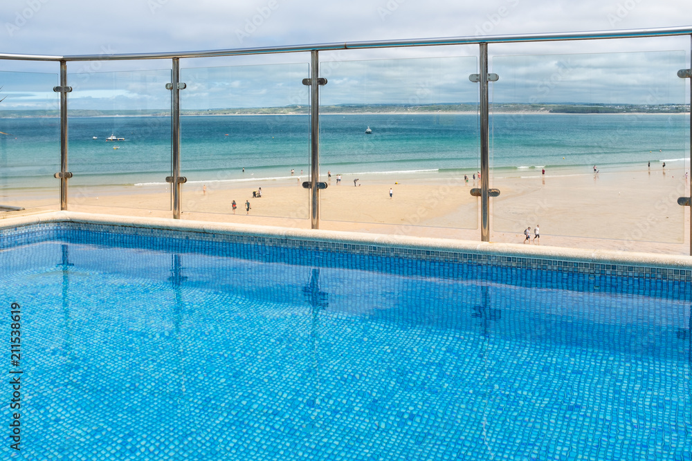 View from a clear, blue swimming pool, over Porthminster Beach, in St Ives, Cornwall.