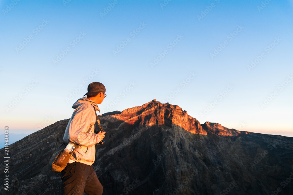 Asian man looking to the top of Mount Agung, the stratovolcano from the Crater Rim before eruption, Bali, Indonesia - obrazy, fototapety, plakaty 